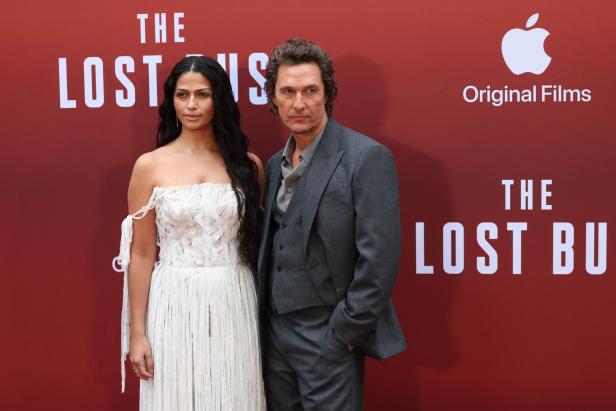 Camila Alves und Matthew McConaughey posieren vor einem roten Hintergrund mit dem Logo von Apple Original Films.