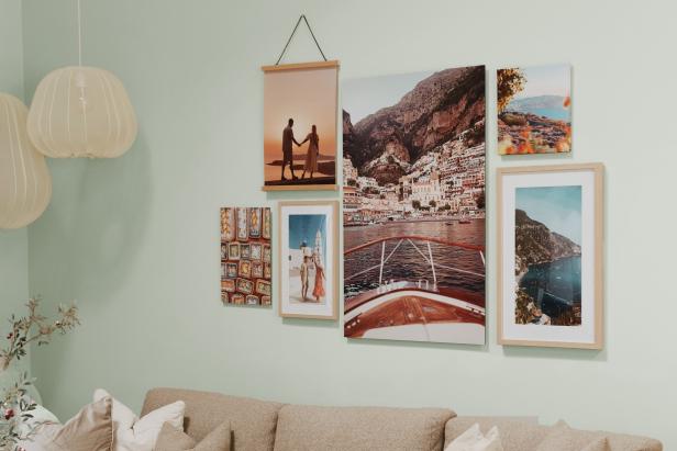 Mehrere Urlaubsfotos als Wandbilder in verschiedenen Formaten und Rahmen dekorieren eine Wohnzimmerwand über einem Sofa.