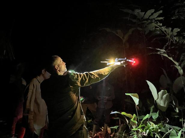 Ein Mann lässt in der Nacht eine Drohne starten.