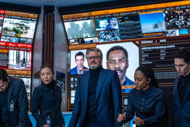 Colin Firth steht in einem Kontrollraum vor Computerwänden. 