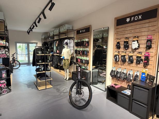 Innenansicht eines Sportgeschäfts mit Mountainbike, Mannequin in Sportkleidung und Wand mit Handschuhen der Marke FOX.