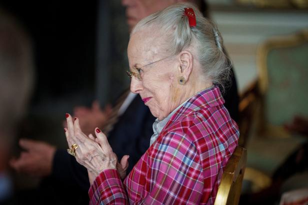 Altkönigin Margrethe II. von Dänemark trägt ein kariertes pinkfarbenes Kostüm und applaudiert bei einer Veranstaltung.