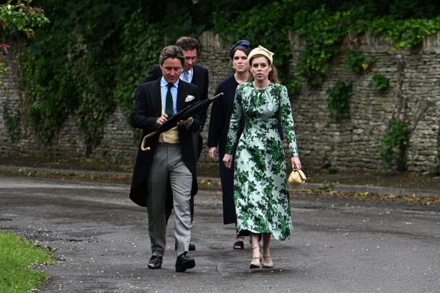 Prinzessin Beatrice und Prinzessin Eugenie gehen mit ihren Partnern in festlicher Kleidung eine Straße entlang.