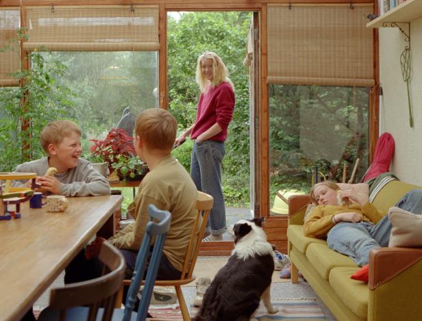 Familienszene mit Mutter und ihren drei Kindern im Wohnzimmer.