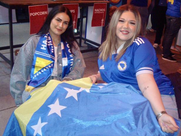 Zwei junge Frauen mit bosnischer Flagge und Fanartikeln beim Public Viewing in Wien.