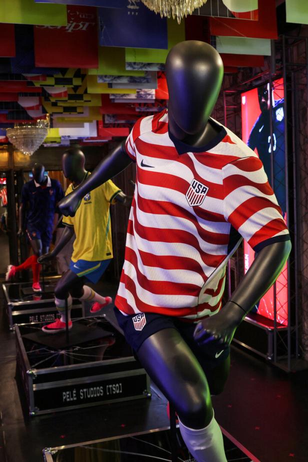 Schaufensterpuppe trägt ein rot-weiß gestreiftes Fußballtrikot der USA mit dunkelblauen Shorts und weißen Stutzen.