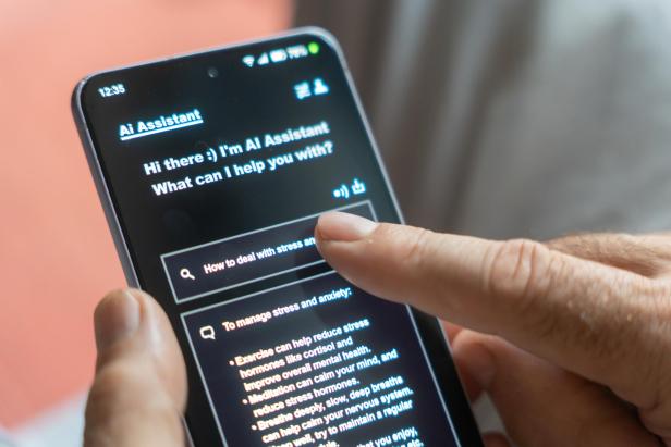 Eine Person tippt auf einem Smartphone und bedient einen KI-Chatbot