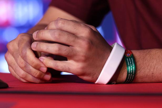 Eine Hand mit zwei Armbändern abgelegt auf einen Tisch.