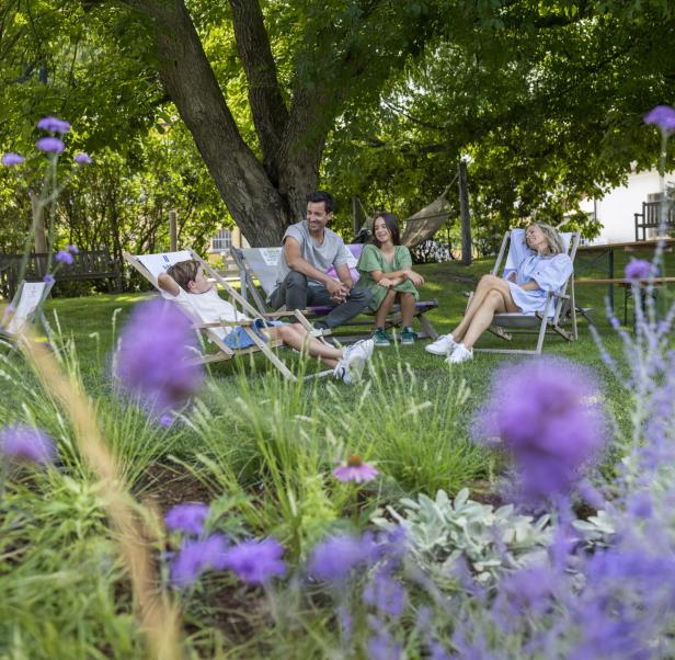 Eine Familie liegt in Liegestühlen in einem Garten  