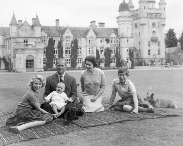 Queen Elizabeth II. mit Prinz Philip, Charles, Anne und Andrew. Sie sitzen auf einer Decke im Gras vor einem Schloss.