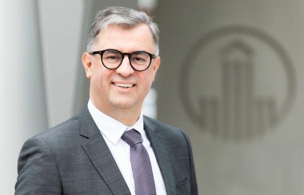 Mark Petronczki von Boehringer Ingelheim steht vor dem Firmenlogo in Wien.