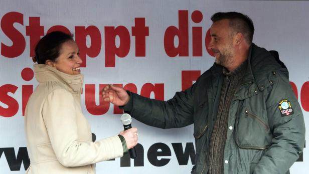 Eine Frau mit Mikrofon im Gespräch mit einem Mann vor einem Banner.
