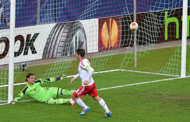Ein Fußballspieler schießt auf das Tor, während der Torwart versucht, den Ball abzuwehren.