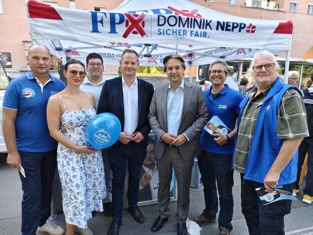 Sieben Personen stehen vor einem FPÖ-Wahlstand mit Dominik-Nepp-Banner und Flyern.