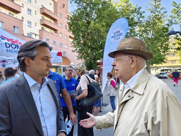 Dominik Nepp im Gespräch mit einem älteren Mann bei der „Kurswechsel Tour“ der FPÖ Wien auf einem belebten Platz.