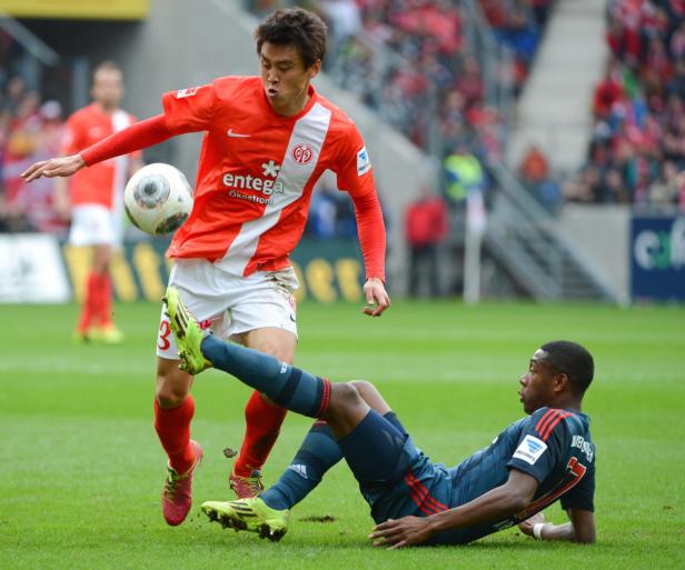 Ein Fußballspieler tritt gegen den Ball, während ein anderer am Boden liegt.