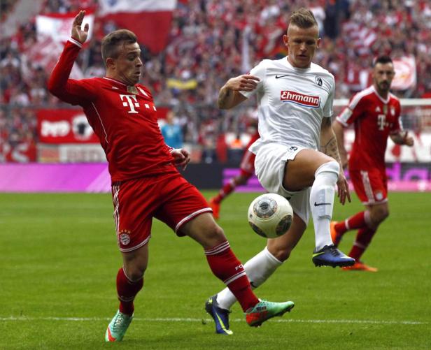 Zwei Fußballspieler kämpfen um den Ball auf dem Spielfeld.