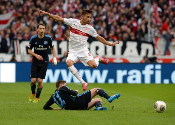 Ein Fußballspieler springt über einen am Boden liegenden Gegenspieler.
