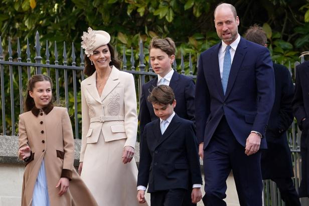 Prinz William und Prinzessin Catherine gehen mit ihren Kindern George, Charlotte und Louis vor einem Zaun spazieren.