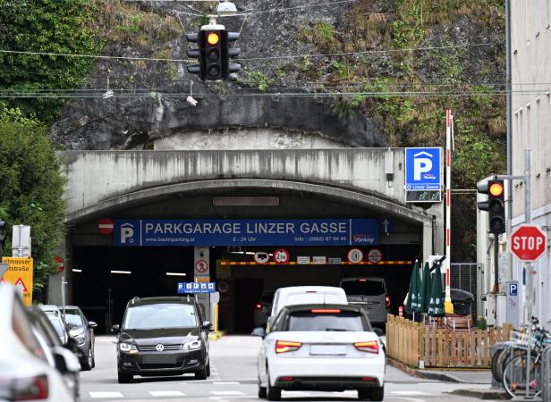 Einfahrt zum Parkgarage Linzer Gasse mit wartenden Autos und roten Ampeln am Tunnel vor Felswand.