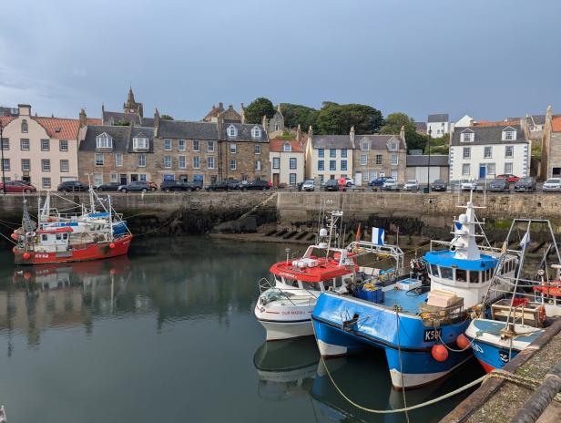 Fischerboote liegen im Hafen von Pittenweem vor einer historischen Häuserzeile.