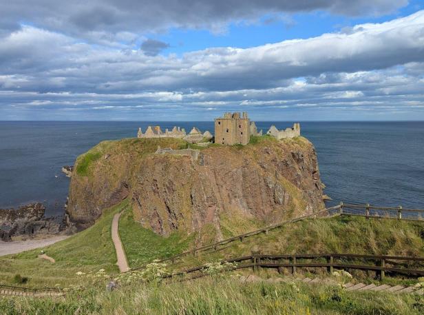 Die Ruine von Dunnottar Castle thront auf einer steilen Klippe über der Nordsee unter einem bewölkten Himmel.