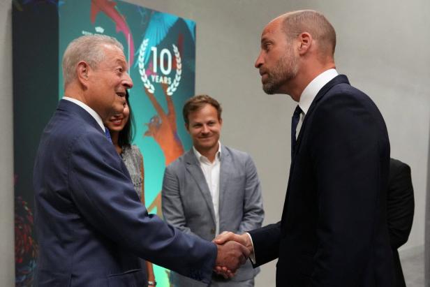 Prinz William schüttelt Al Gore vor einem Banner zum zehnjährigen Jubiläum die Hand.