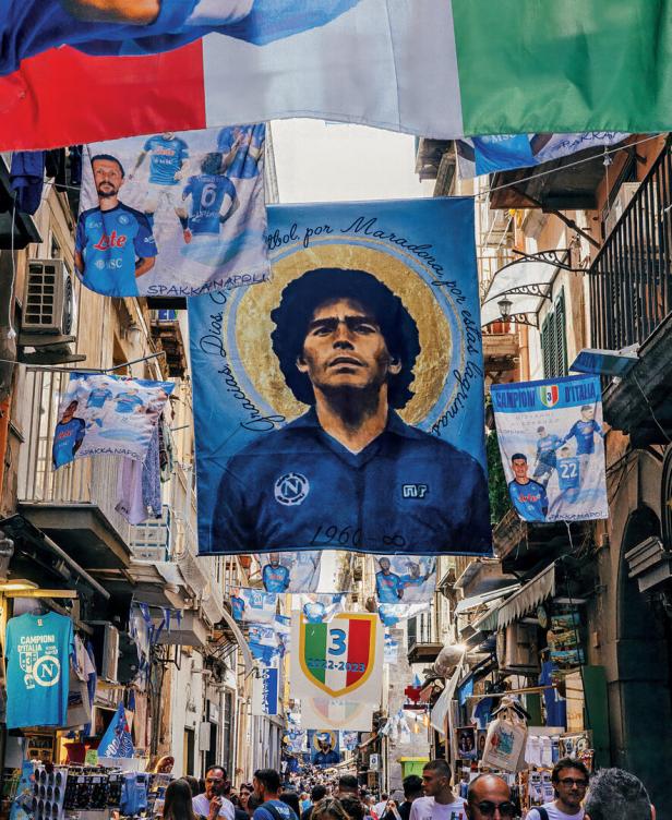 Enge Gasse mit vielen Fußballfahnen und Maradona-Bannern, überfüllt mit Menschen.