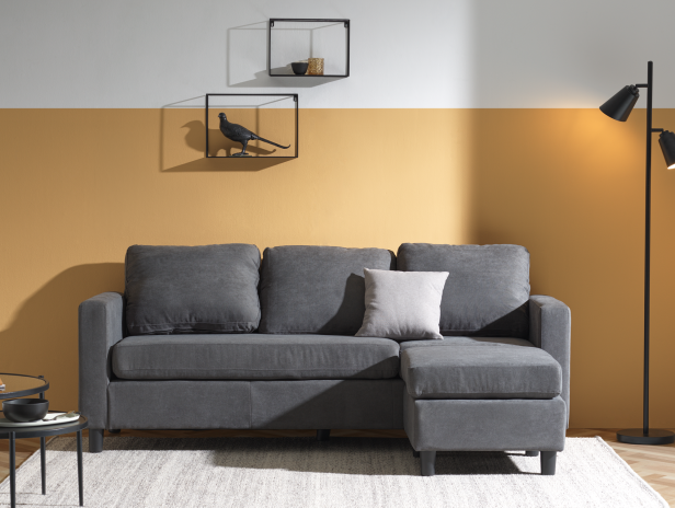 Graues Ecksofa mit Chaiselongue in einem hellen, modern eingerichteten Wohnraum.
