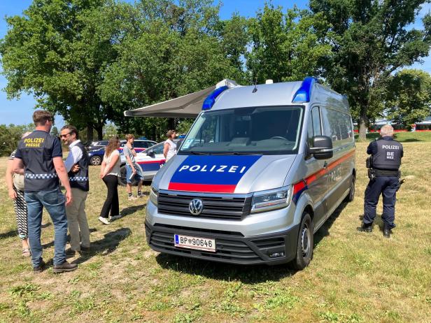 Polizeiwagen und Einsatzkräfte bei einer Sicherheitsbesprechung im Grünen.