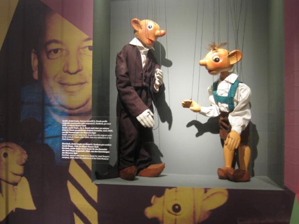 Zwei Marionettenpuppen in einer Vitrine, darunter Spejbl und Hurvínek.