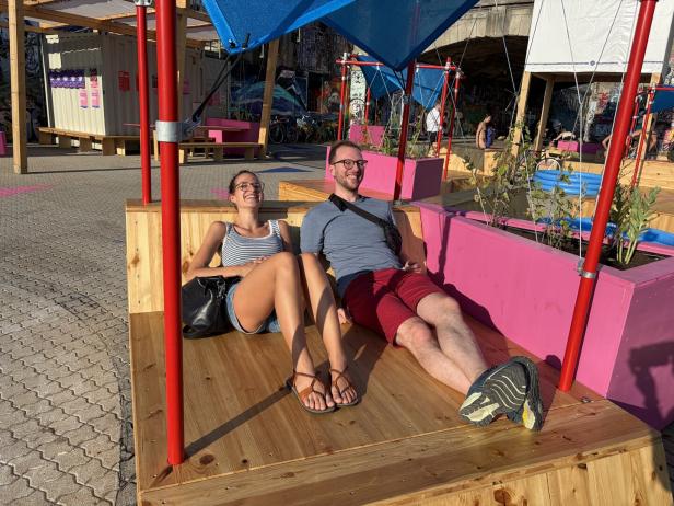 Zwei Menschen liegen auf den neuen Holzbänken und sonnen sich.