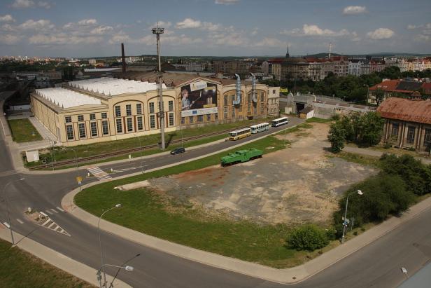 Luftaufnahme einer Stadtlandschaft mit einem großen Gebäude und mehreren Bussen.
