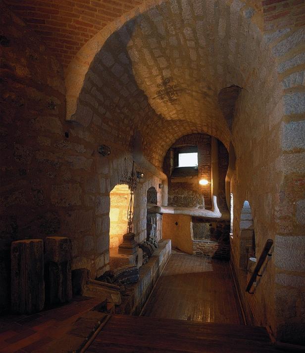 Ein gewölbter Gang mit Steinmauern und einem kleinen Fenster am Ende.