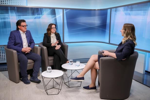 Zwei Gäste sitzen in einem Fernsehstudio in Sesseln einer Moderatorin gegenüber, die sie interviewt.