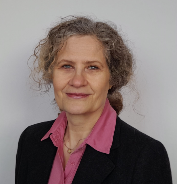 Anja Harsch mit pinkem Hemd und schwarzem Blazer vor neutralem Hintergrund.