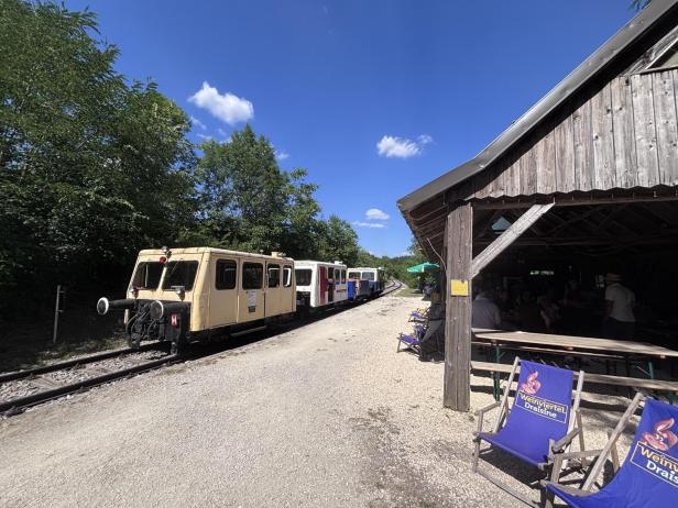 Gelber Zug vor einer Holzhütte.
