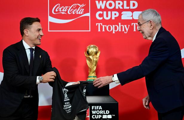 Fabio Cannavaro und Alexander Van der Bellen präsentieren den FIFA World Cup 26 Pokal vor einem Coca-Cola-Hintergrund.