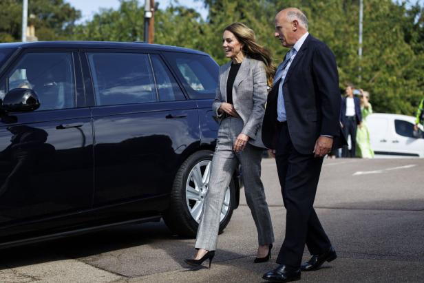 Prinzessin Kate geht in einem grauen Hosenanzug neben Jamie Lowther-Pinkerton in Anzug an einem schwarzen Auto vorbei.
