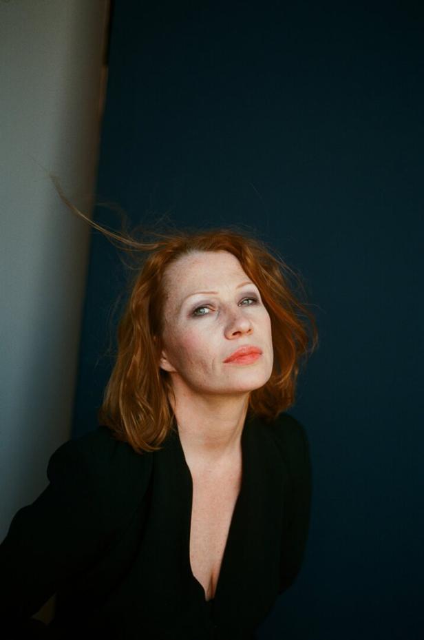 Birgit Minichmayr vor dunklem Hintergrund.