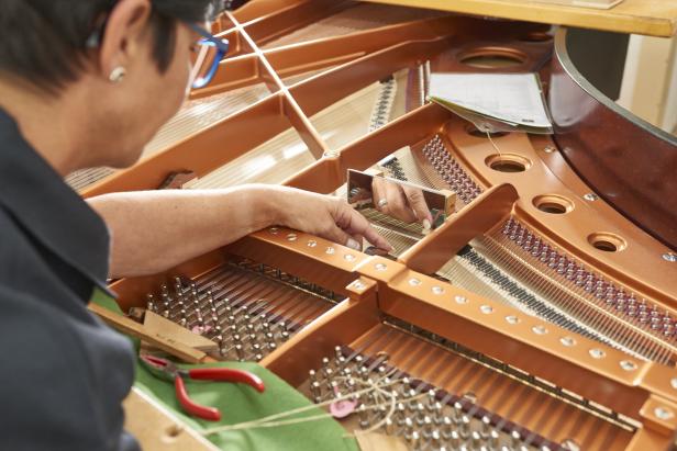 Eine Person arbeitet mit einem Spiegel an der Mechanik im Inneren eines Flügels.