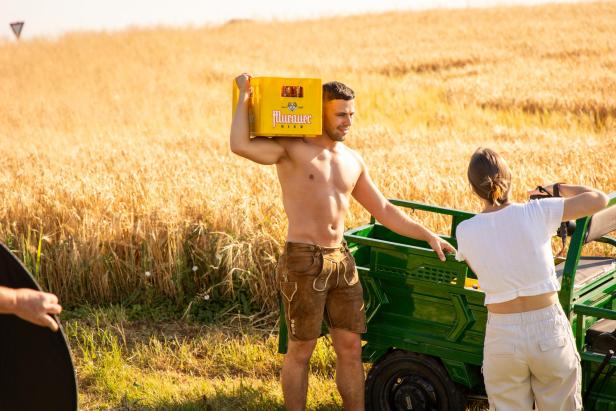 Ein oberkörperfreier Mann schultert eine Bierkiste
