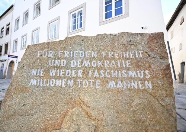 Gedenkstein mit der Aufschrift „Für Frieden, Freiheit und Demokratie“ vor einem weißen Gebäude.