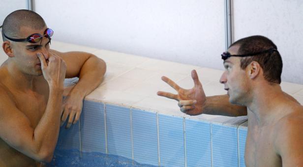 Zwei Schwimmer unterhalten sich am Beckenrand.