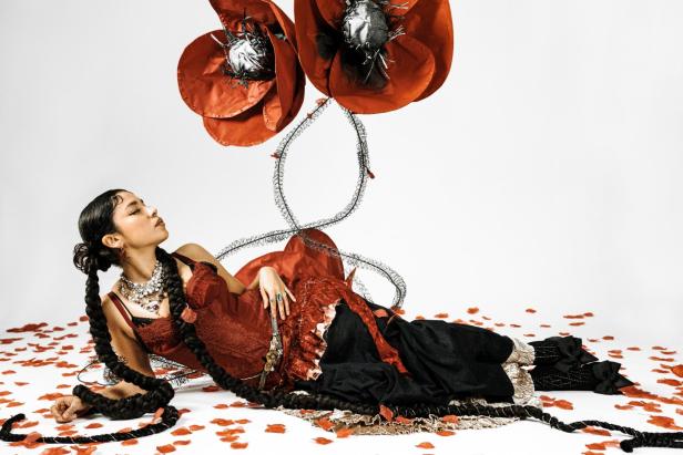 Musikerin Tamara Flores liegt zwischen Blütenblättern am Boden
