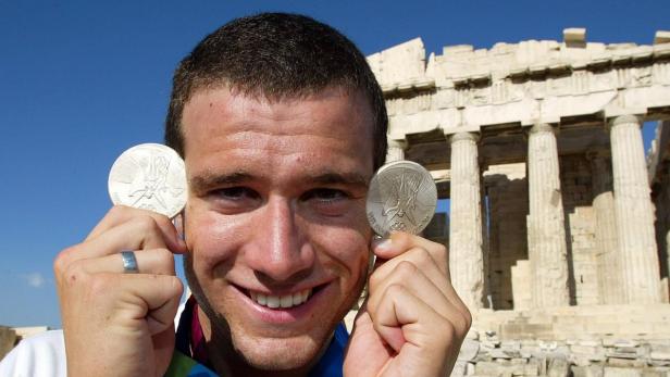 Ein Mann posiert mit zwei Silbermedaillen vor dem Parthenon in Athen.