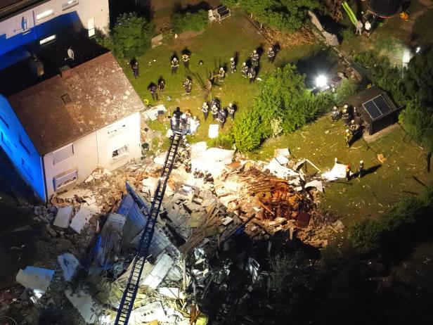 Zerstörtes Wohnhaus nach Gasexplosion, Einsatzkräfte zwischen Trümmern.