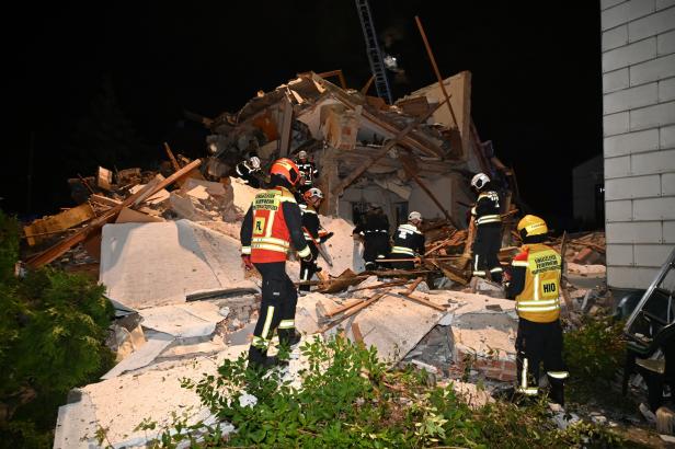 Feuerwehrleute durchsuchen nachts die Trümmer eines eingestürzten Hauses nach möglichen Verschütteten.