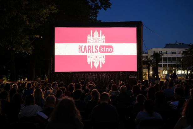 Open-Air-Kino bei Dämmerung mit Publikum vor einer großen Leinwand.