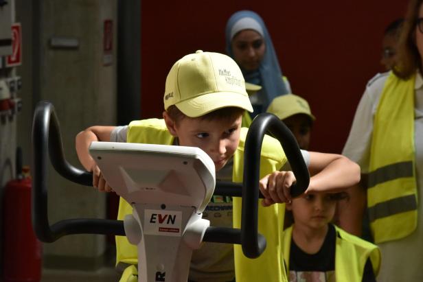 ein Bub sitzt auf einem Ergometer und tritt in die Pedale